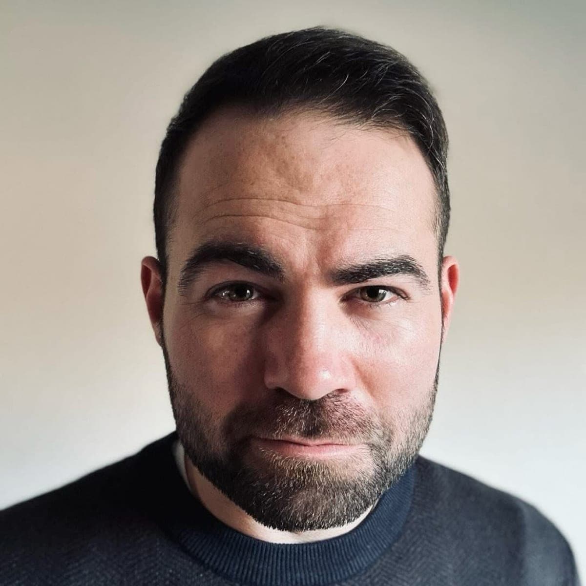 Kyle Coogler, headshot portrait, looking directly at the camera in a dark sweater